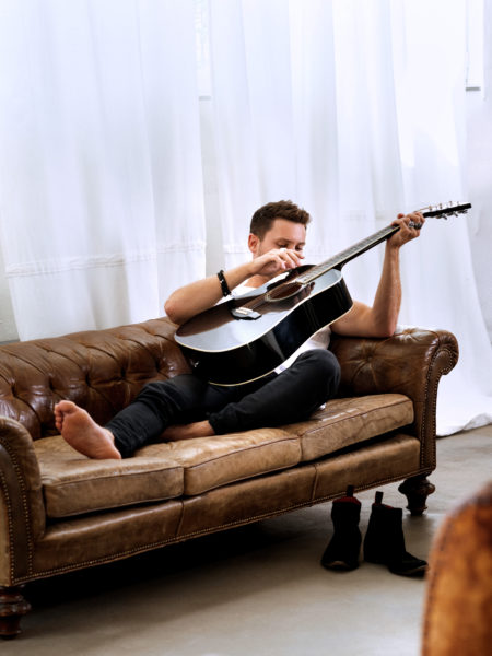 Bastian Baker relaxed: Mit seinem Instrument auf dem Sofa. 
©Pascal Triponez