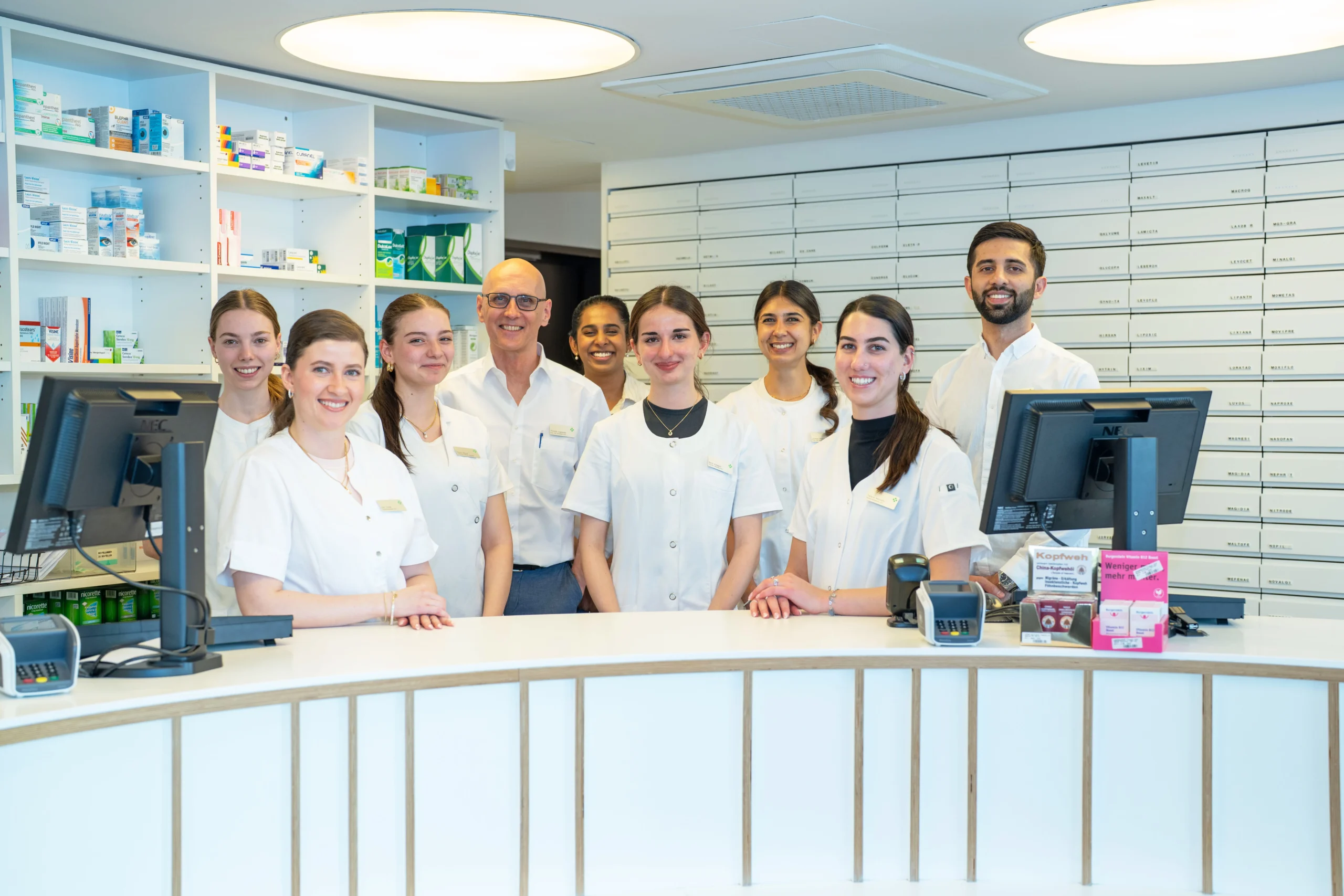 L'équipe de la pharmacie se tient derrière le comptoir et pose ensemble pour une photo.
