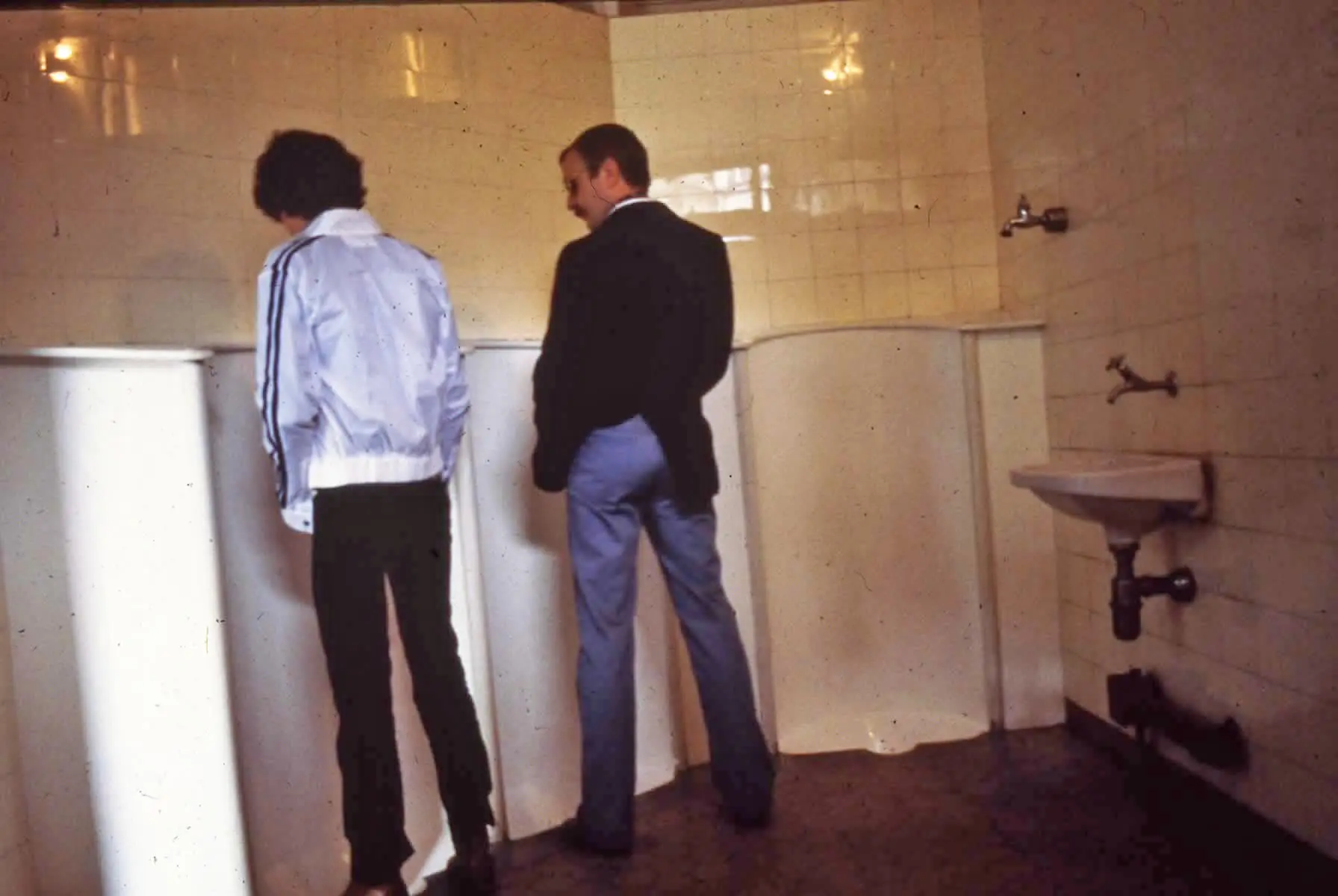 Zwei Männer stehen nebeneinander an einem Urinal.