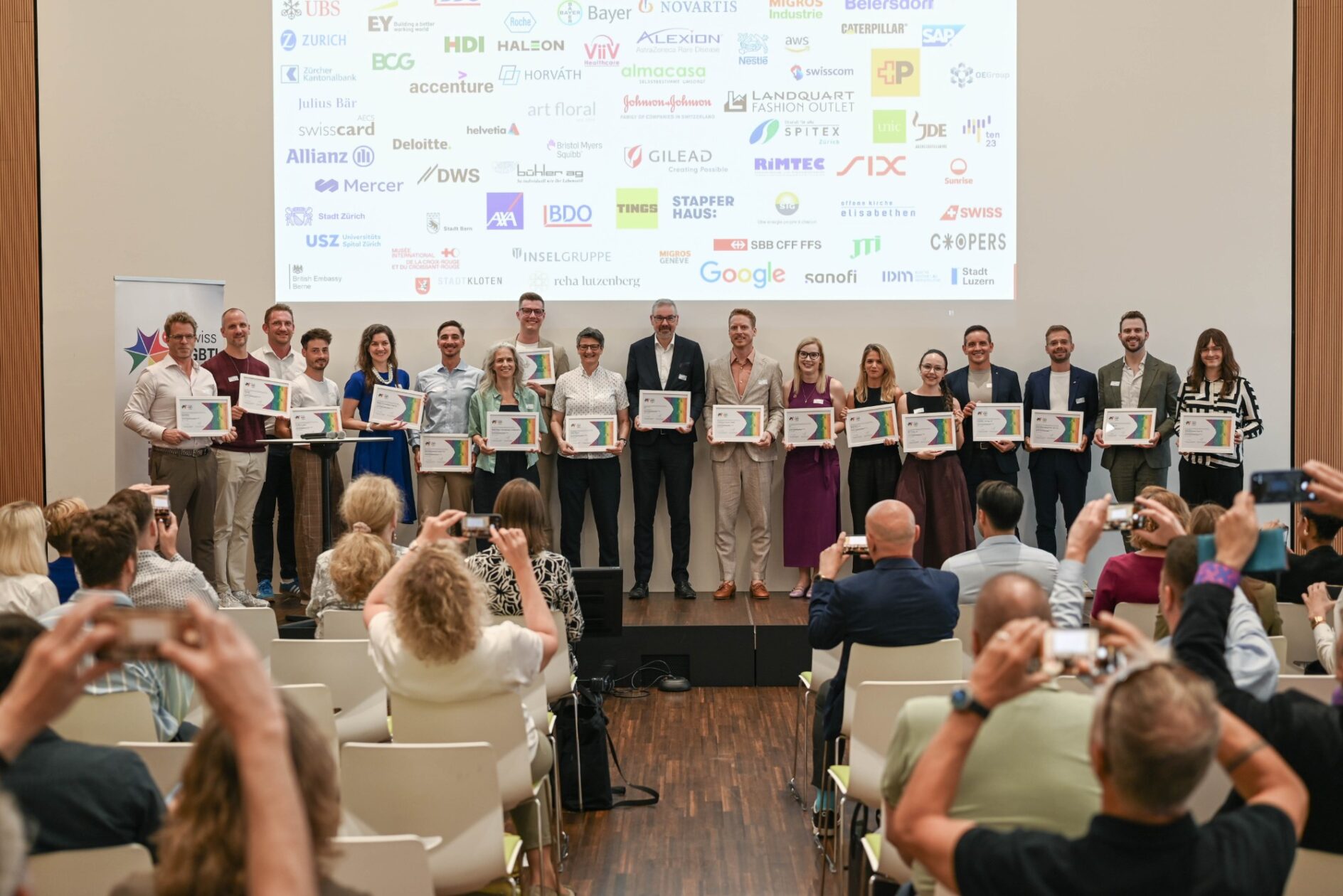 Gruppenbild der Vertreterinnen und Vertreter der 20 ausgezeichneten Organisationen auf der Bühne bei der Schweizerischen Post in Bern