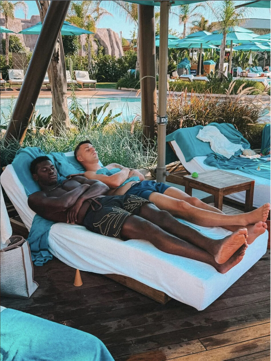 Zwei Fussballer entspannen auf Liegen an einem Pool im Ferienresort