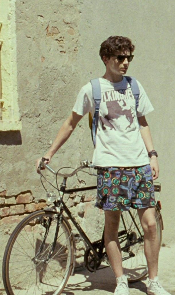 Elio mit Sonnenbrille und gemusterten Shorts neben seinem Velo