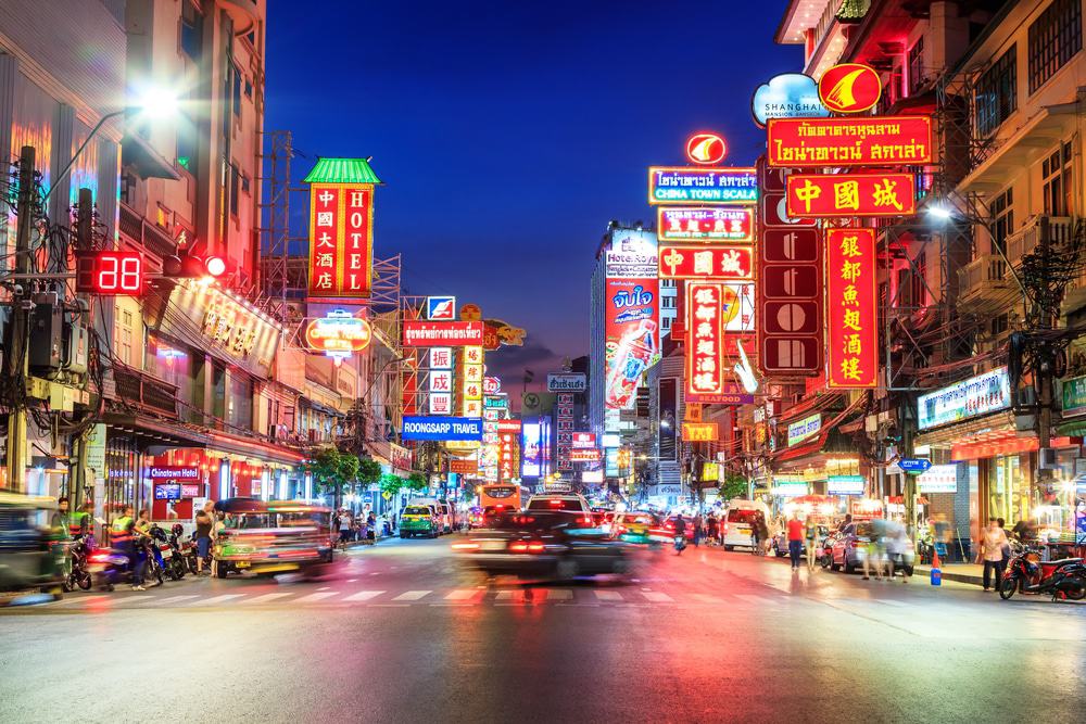 Chinatown in Bangkok am Abend mit leuchtenden Reklameschildern über der Strasse