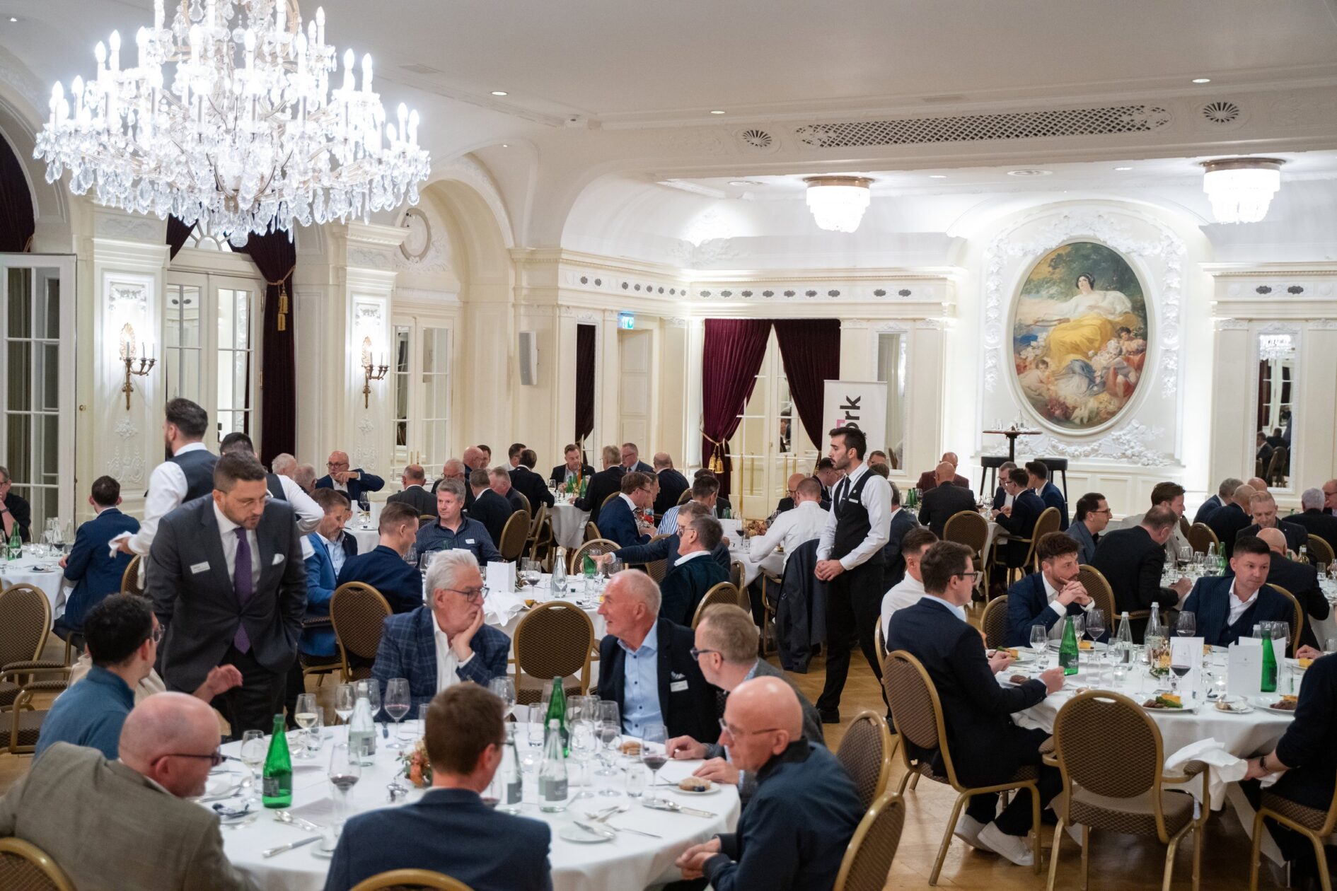 Gäste an runden Tischen unter einem Kronleuchter im Saal des Bellevue Palace Bern