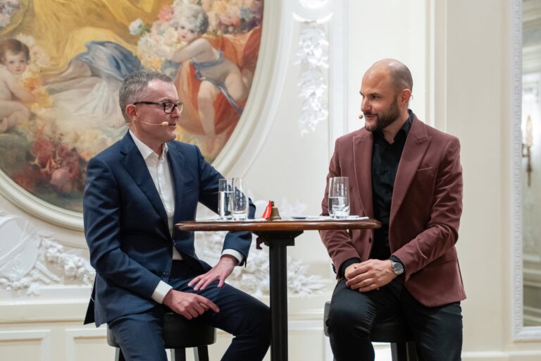 Jürg Lauber und Michael Rauchenstein an einem Stehtisch auf der Bühne