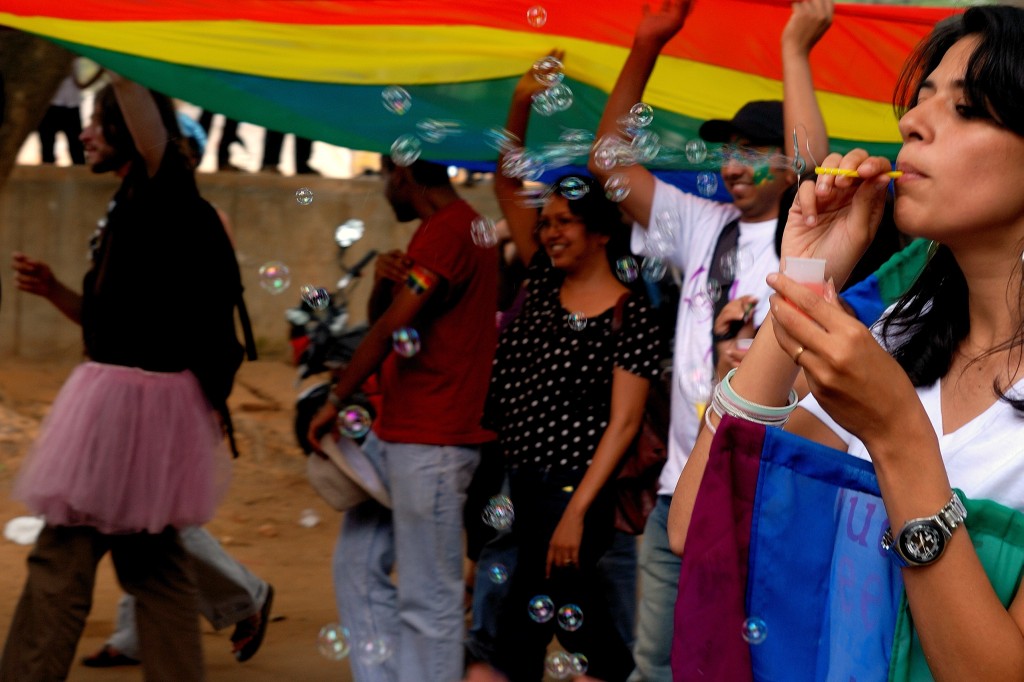 Menschen tanzen unter einer grossen Regenbogenfahne und pusten Seifenblasen an der Pride in Bengaluru 2009