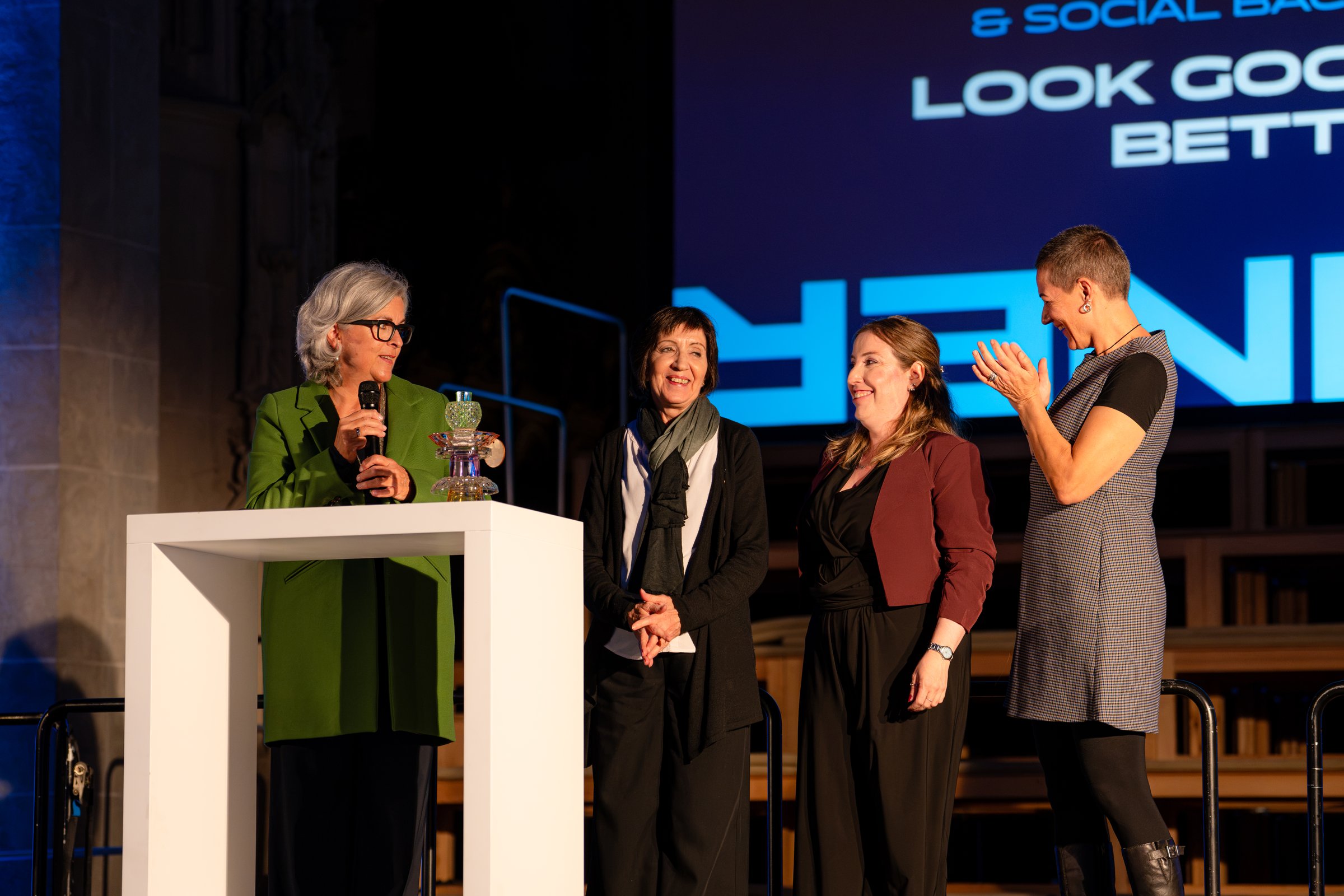 Das Team von Look Good Feel Better auf der Bühne, eine Person spricht ins Mikrofon