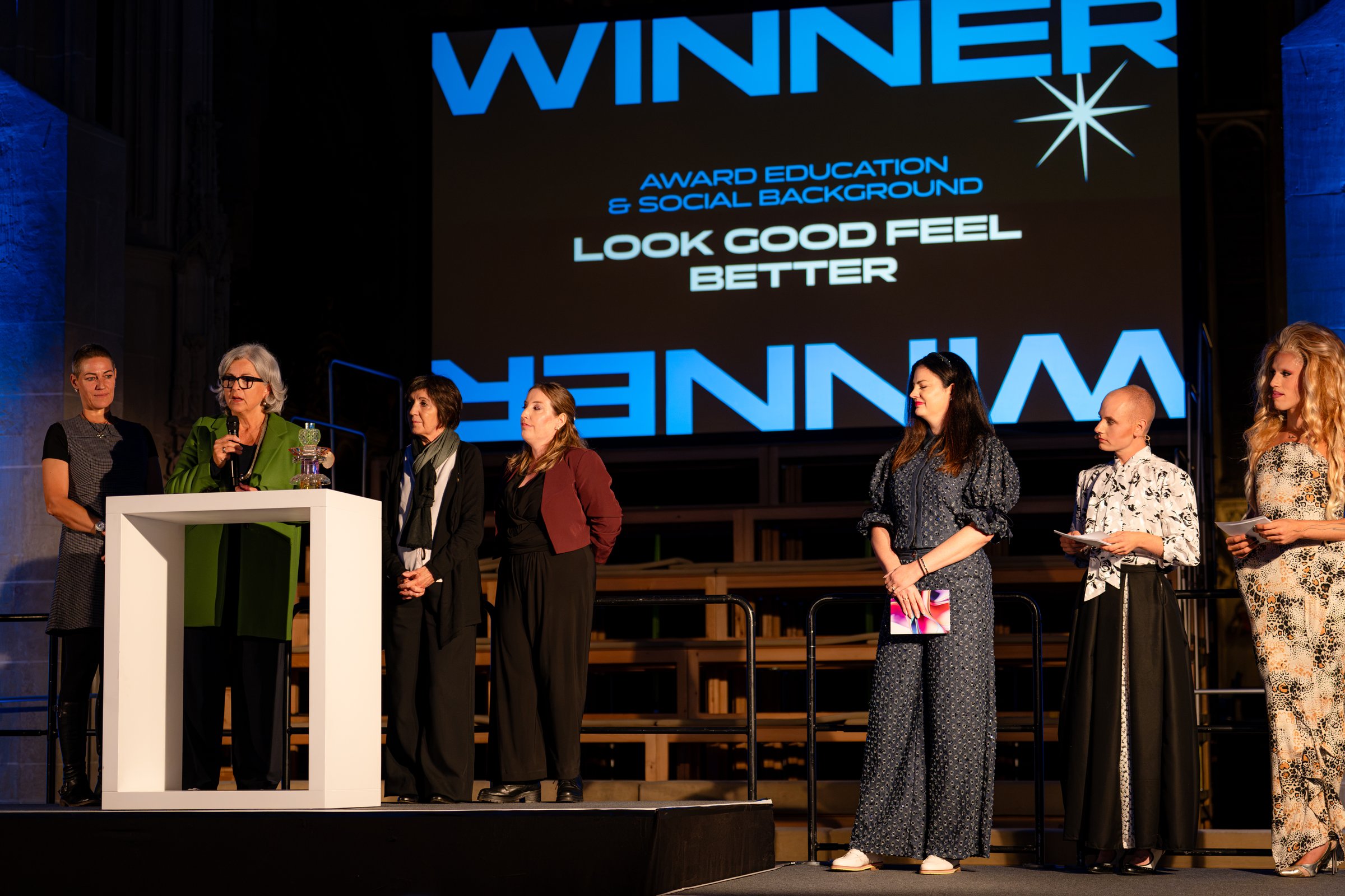 Viele Personen auf der Bühne vor der Leinwand «Winner – Award Education & Social Background – Look Good Feel Better»