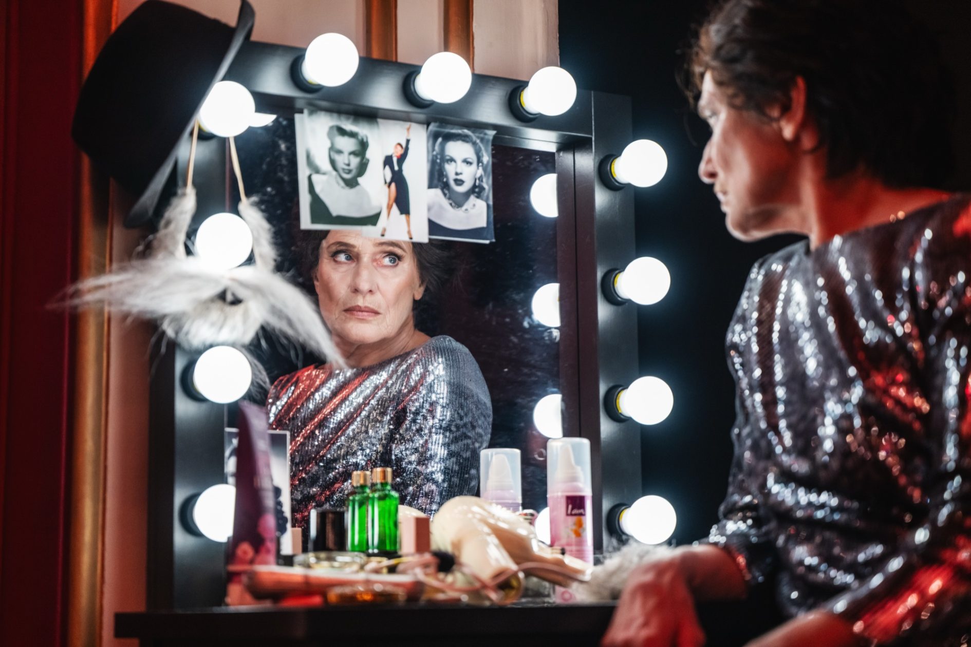 Eine Frau sitzt am beleuchteten Garderobenspiegel mit Fotos von Judy Garland
